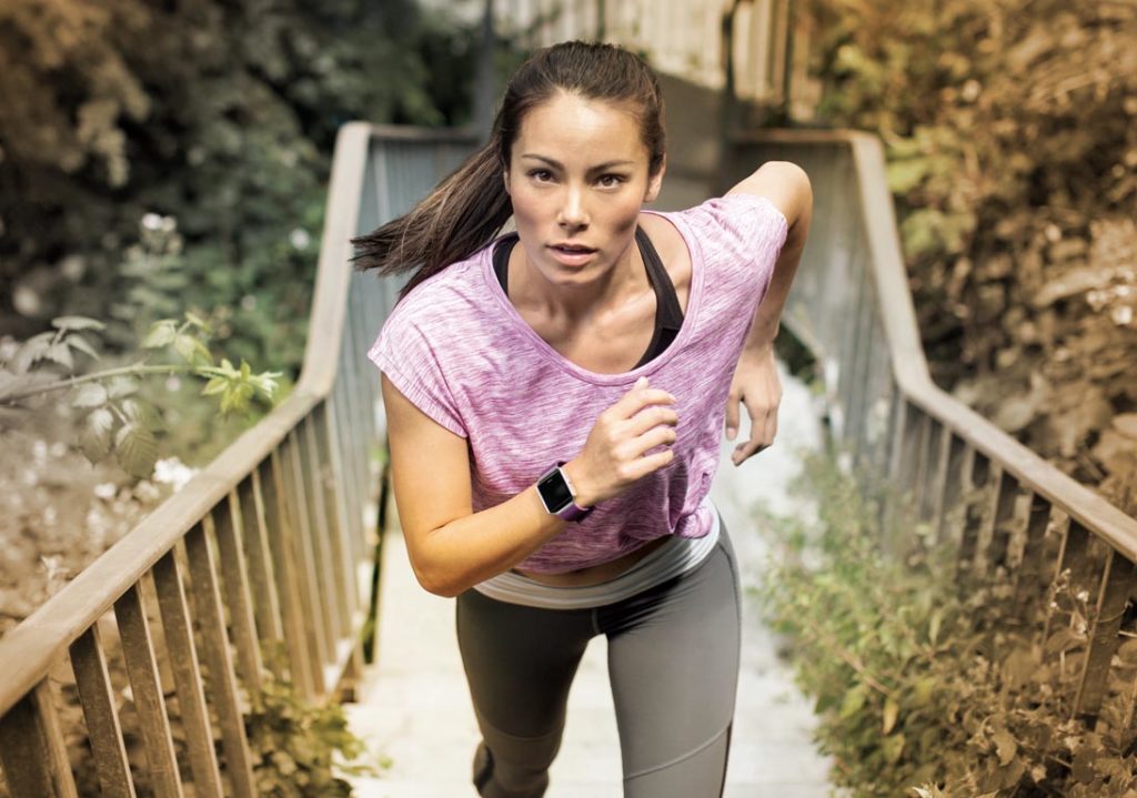 Female jogging up stairs wearing blaze sport Fitbit