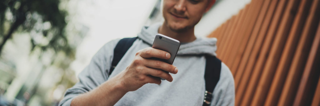 Millennial Gen Z college student using iphone to text or play mobile gaming apps