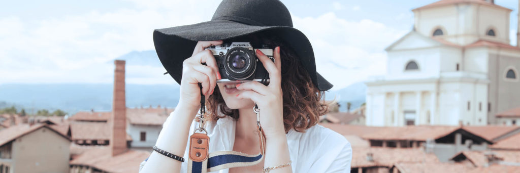Girl tourist millennial holding analog camera shooting photos while on vacation
