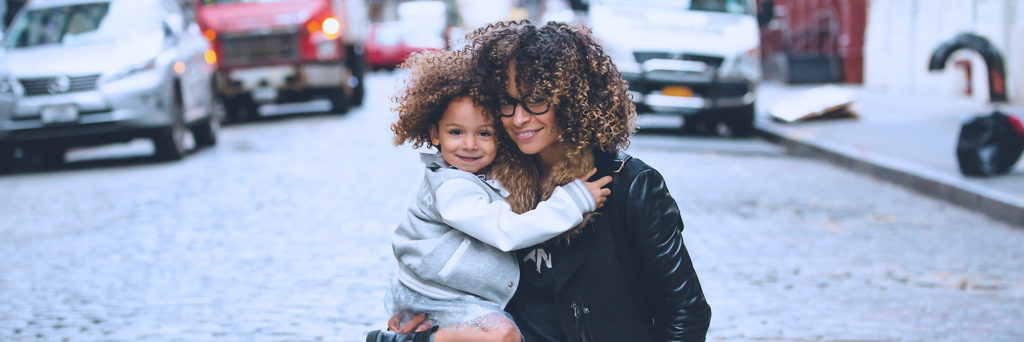 Young adult mother and her daughter hugging in the middle of a cobblestone street
