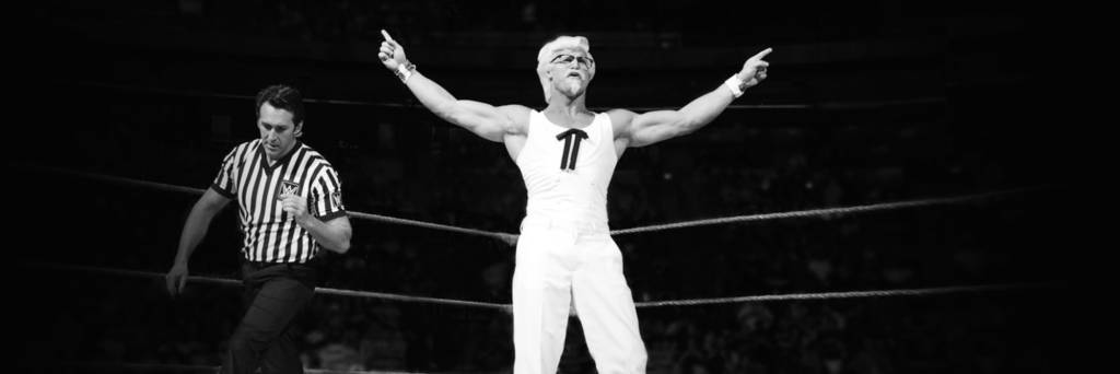Colonel Sanders standing in champion stance in wrestling ring