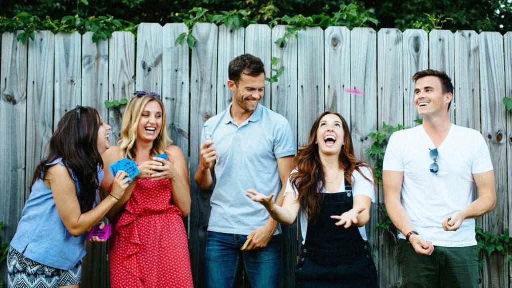 Group of people having fun throwing WYB playing cards into the air