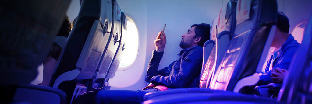 Millennial on airplane using smartphone