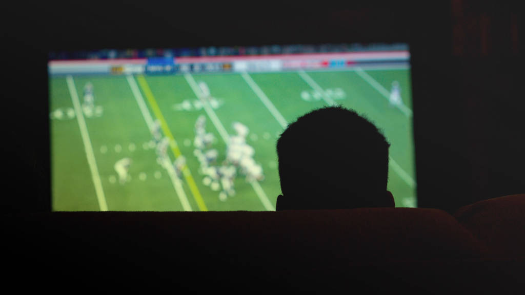 Man watching Superbowl on TV in the dark